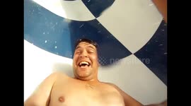 Man gets sent backwards down a waterslide and splashes down into the water