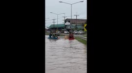 Locals play in kayaks on flooded road in Thailand