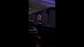 Business class passenger seen using FEET to operate touch-screen TV
