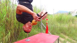 Man does a head stand on a steel pipe and plays the flute