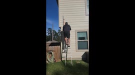 Man struggles to hang lights as his ladder begins to tremble under him