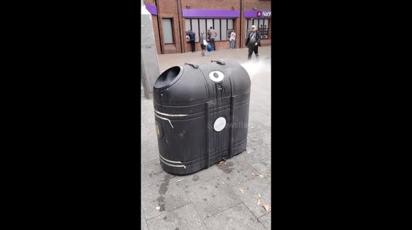 Rubbish bin on fire caused by cigarette butts in Waltham Station Square, London, UK.