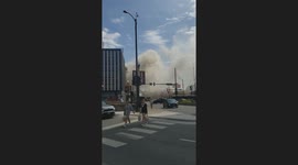College students walk near Loyola campus as a raging fire consumes a nearby storage building.