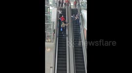 Stubborn elderly people block passage as they attempt to walk wrong up airport escalator