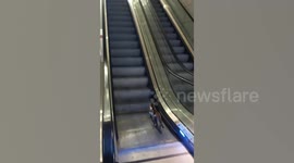 Cat struggles to climb wrong way on escalator at airport