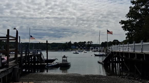 American flags flying at two waterfront properties on the York River in York, Maine. One is at half mast for slain podcaster Charlie Kirk while the other is not.