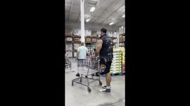 A 6’10” giant doing grocery shopping in a regular-sized store — everything around looks miniature, from shelves to shopping carts.