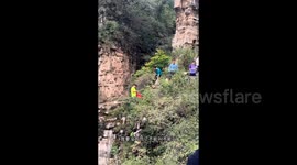 Cheers as tourists rescue Chinese woman dangling off cliff after slipping whilst taking photos