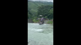 Bus topples over while carrying passengers through fast-flowing river
