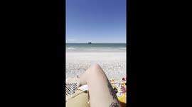 Woman's picturesque Florida beach view interrupted by boat advertising coffee