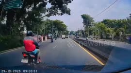 Motorcyclist knocked over by a truck scrambles to avoid wheels