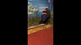 Two men struggle to pull tall grass and fall over in Zhejiang, China