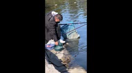 Man feeds fish while fishing in Shandong, China
