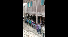 Villagers carry wooden house to a new location
