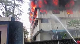 Dyeing factory caught in fierce inferno, thick smoke rises from building roof, emergency responders work tirelessly to control fire