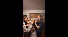 2 Girls Play 1 Violin While A Guy Plays Piano Laying on His Back