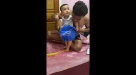 Father uses carrier bag as harness to help baby learn to walk
