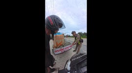 Kind policeman fits tail light on elderly scrap vendor’s cart on busy truck route