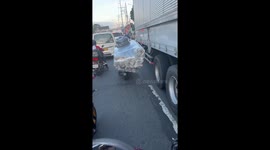 Sofa seen being carried through traffic on back of motorcycle
