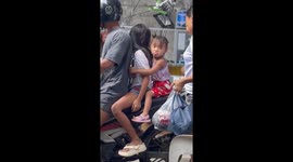 Mischievous girl makes funny faces while riding on a motorcycle in Tondo, Manila, Philippines