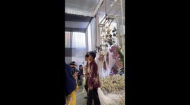 Cat jumps onto bride's dress during aisle walk before being quickly removed during wedding