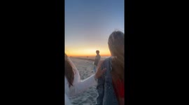 Man holds lit firework in hand during sunset beach celebration in Washington