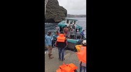 Crew load cargo onto boat bouncing up and down on choppy sea