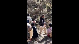Hikers carry small dog on stick down mountain in Shaanxi, China