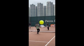 Players rally with giant tennis ball using huge rackets