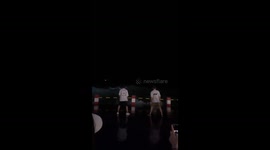 Two men perform synchronized jump moves as wave crashes in Guangxi