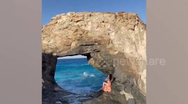 Tourist posing on beach cliff gets swept away by giant wave
