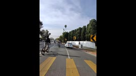 Car Races Through Large Pack Of Bicycles