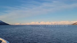 Raw footage from a boat travelling through the norwegian arctic cercle in April. Crystal-clear open Arctic waters (no floating ice), dramatic iced-covered mountain in thawing, and a clear sky. Authentic strong polar wind sound throughout.