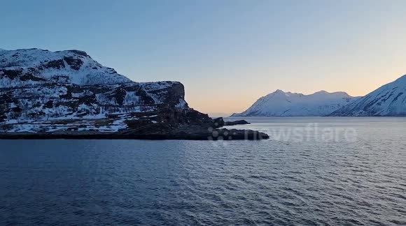 Raw extended unedited footage of a ship traveling through the Norwegian Arctic Circle. Lighthouse, spring thaw, clear blue sky, diffused red and blue sunset colours across the sea surface (subtle optical phenomenon) Natural sound of the strong north wind