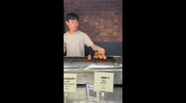 Market visitor tucks into grilled spicy sausage street food