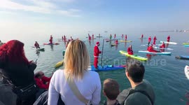 Festive surprise as dozens of Santas emerge from the sea on paddleboards stunning beachgoers in Greece