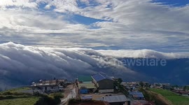 Clouds flow over mountains like a giant waterfall