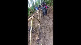 Young hiker slips on muddy track while he descends mountain with friends
