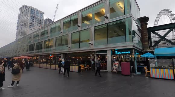London Eye Side View from Pedestrian Zone – Thames Riverside with People and Restaurants (Editorial Use)