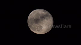 Close up of the Moon with a plane seen flying across it seen over Greenwich
