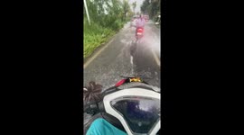Motorcycle rider drenched by driver speeding through puddle