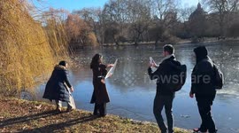 Londoners and tourists have fun tossing ice on frozen lake in St James’s Park, London