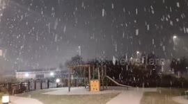 Evening snow showers blanket a playground in Warrington, England, UK