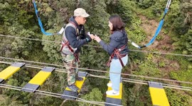 Girl cries with fear then joy as boyfriend proposes on 1,000ft rope walk bridge