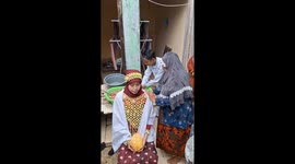 Videos captures an intimate moment of a traditional cultural ritual held in a modest family courtyard, where community, heritage, and symbolism come together. At the center, a woman sits calmly, wearing traditional attire adorned with intricate woven orna