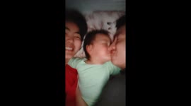 Chinese baby melts hearts by sleeping between parents and kissing them goodnight