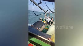 Fishermen stand on overturned boat in desperate sea rescue after capsize leaves one dead