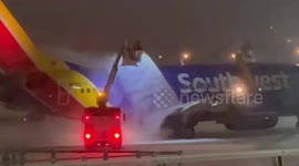 Southwest aircraft de-iced during nighttime snowfall in Rochester, New York, USA