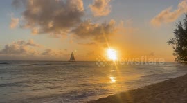A yacht sails past the setting sun on Errol Barrow Day in Barbados