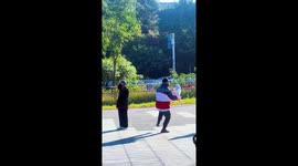 Grandfather practices Tai Chi while holding his grandchild in China